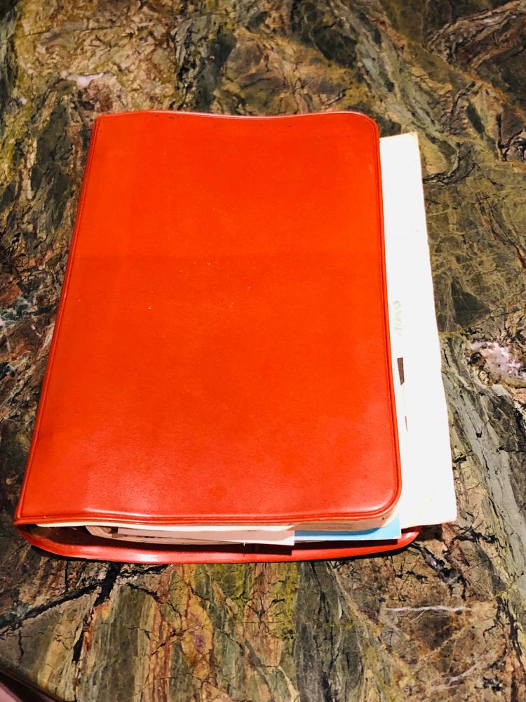 A closed, full journal with a red cover.
