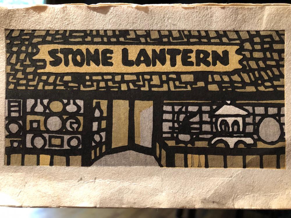 A letterpress illustration of a storefront with a stone facade and sign that reads "Stone Lantern".