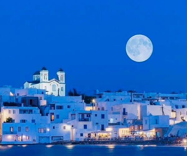 Illuminated Greek town under a full moon.