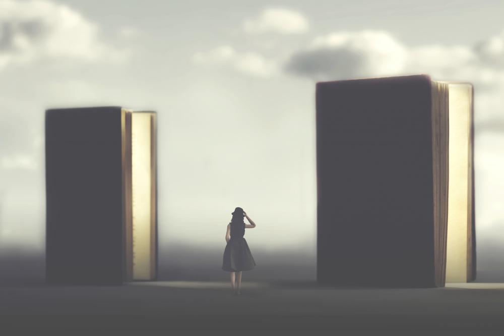 A woman facing the opposite direction stands in the middle of two gigantic books.
