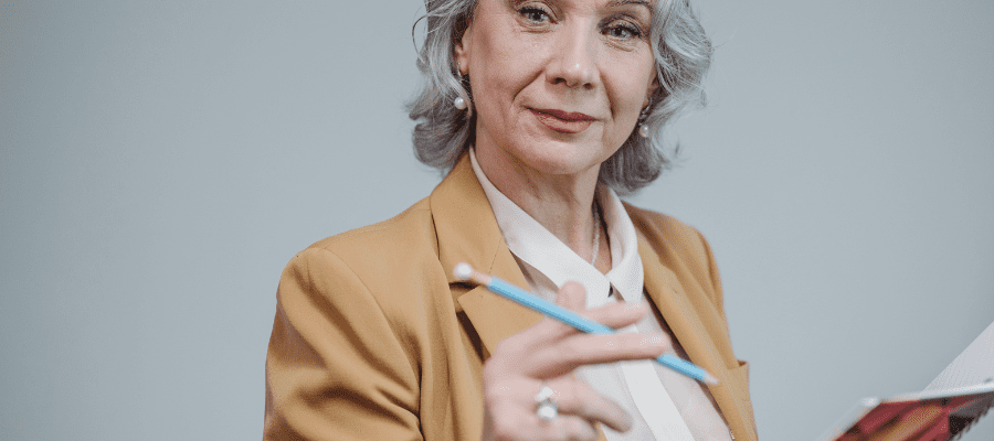 Gray-haired woman holding pen and journal, to symbolize how to Find Your Passion in Life