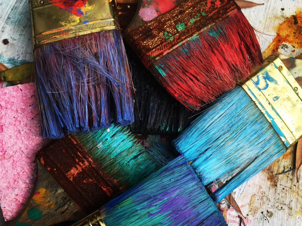 Thick paintbrushes with bold colored paint (pink and blue and purple), to symbolize authentic living