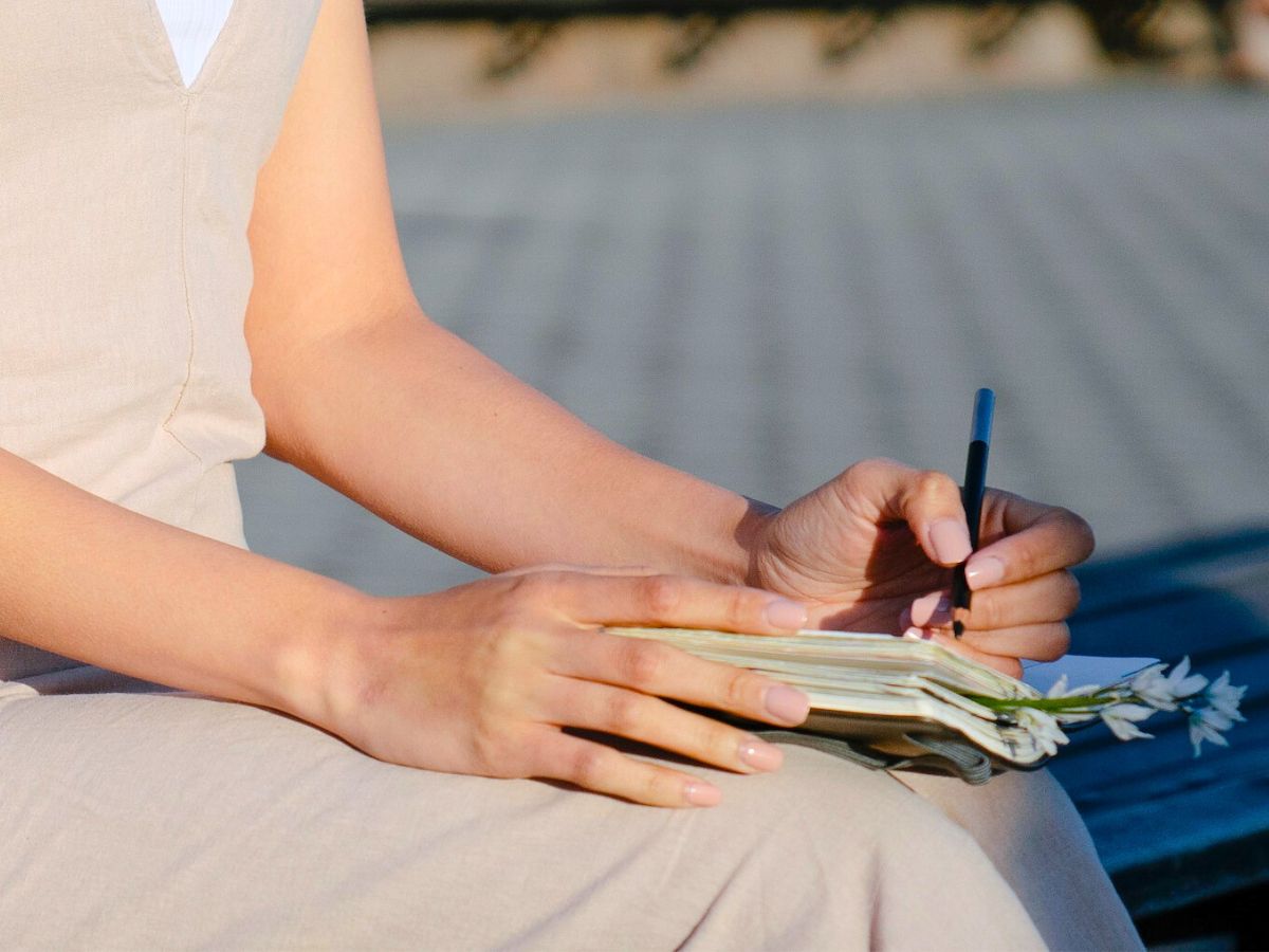 Woman sitting, writing in pocket journal, creative thinking, creative breakthrough
