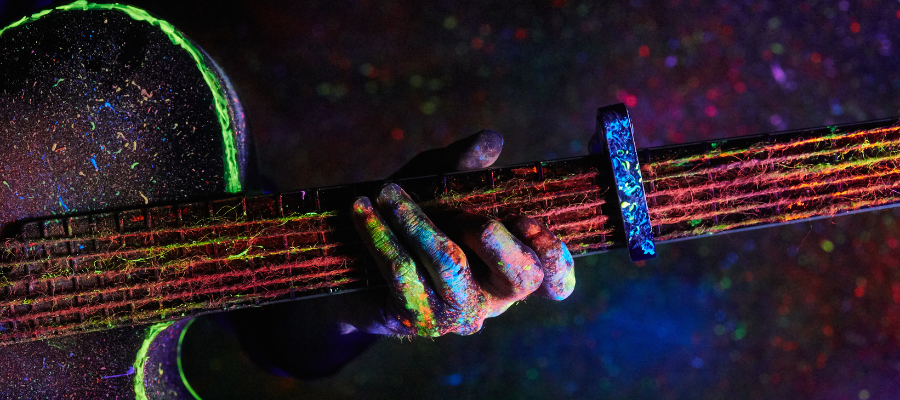 be fearless, hand on guitar fretboard, dimly lit with neon paint on the guitar and hand