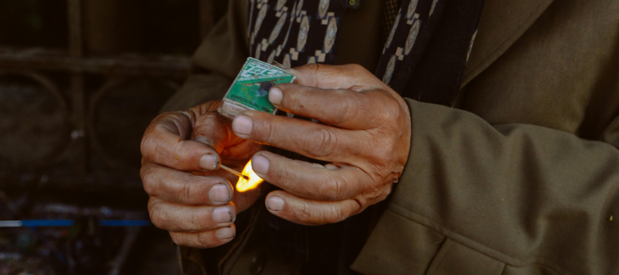 Photo of a person's hands holding a matchbox and lit match, representing the metaphor of a box of matches as a safety net for building trust in yourself.