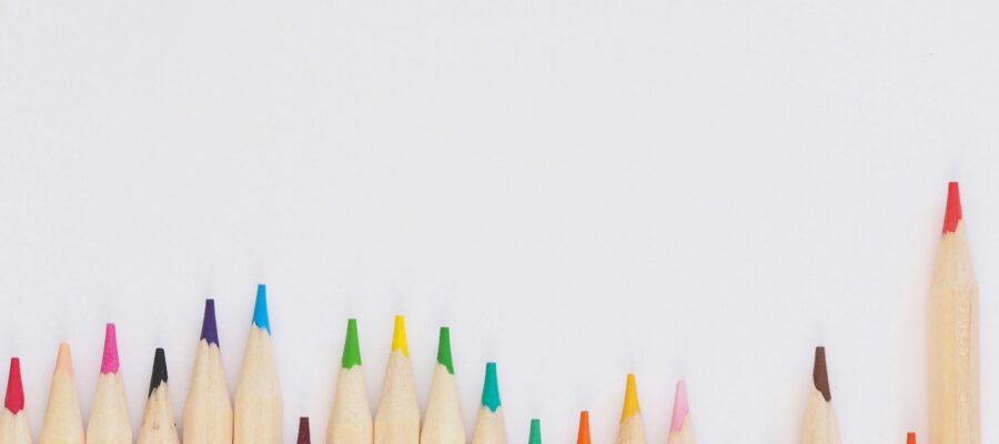 neutral background with colorful pencils representing how writing a book can surcharge your business