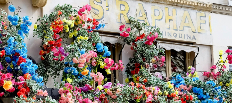 Parisian storefront with blue, pink, yellow, and red flowers to symbolize how to become who you are when traveling
