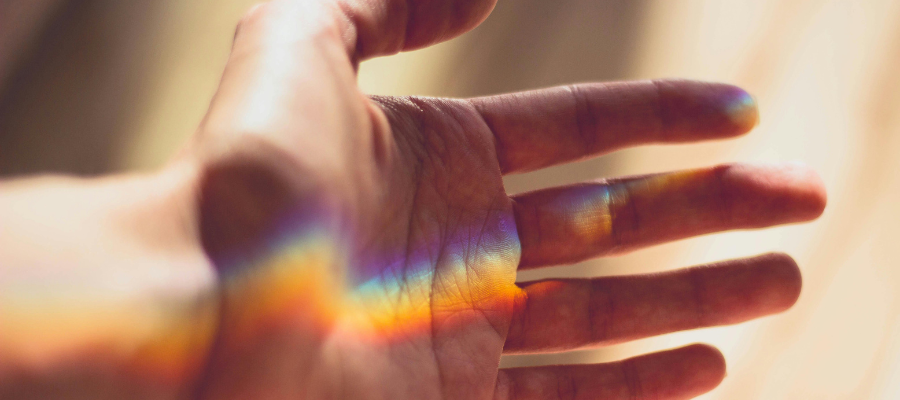 outstretched palm with light prism rainbow horizontally along it, to symbolize paying attention to the beauty around you