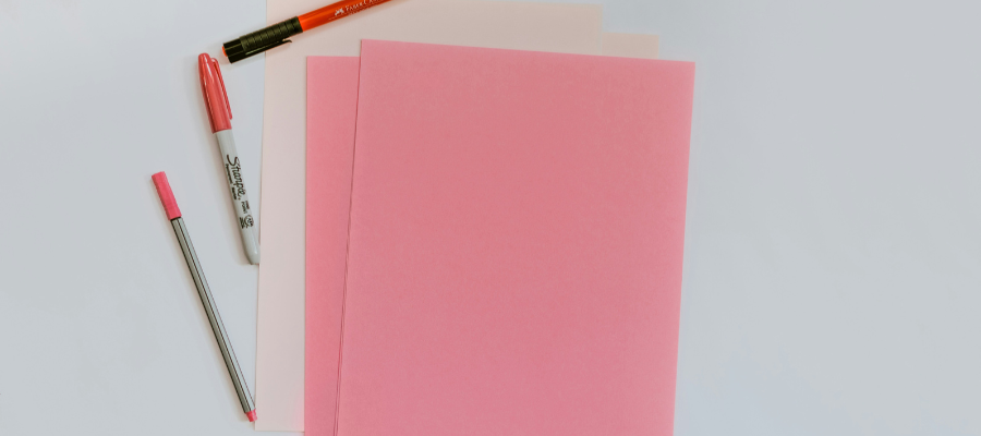 pink and white sheets of paper with pink and orange pens, to symbolize the journaling needed to learn how to figure out what you want