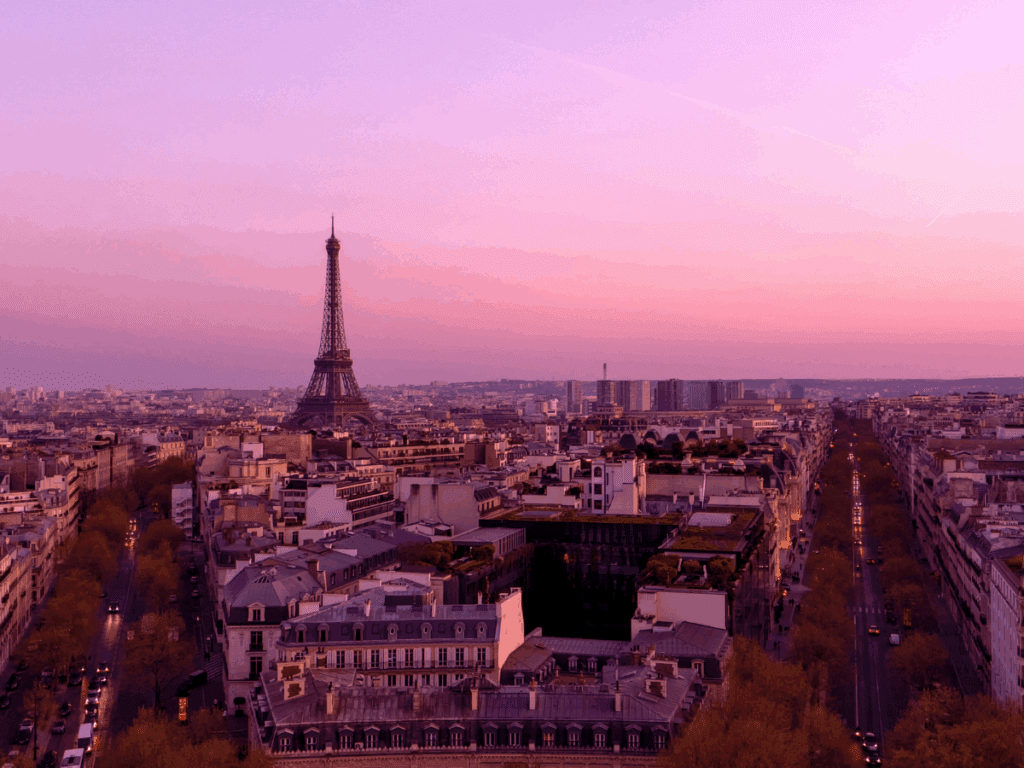 The Eiffel Tower silhouetted against a vibrant sunset sky, with warm hues of orange, pink, and purple fading into the evening, representing French Brands