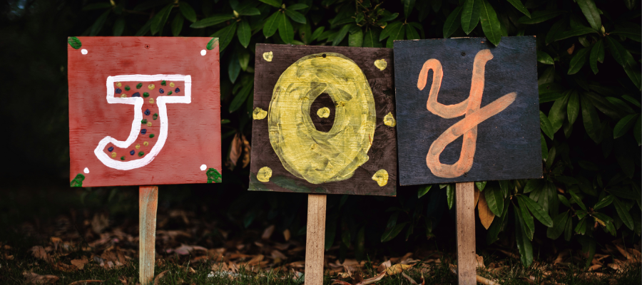 cultivate joy; three uniquely hand-painted signs spell out J-O-Y, joy.