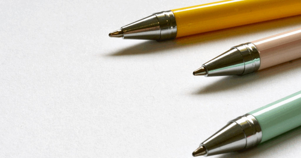 3 ballpoint pens (yellow, pink, and green respectively) on white background, to symbolize journaling to answer how to know what you want