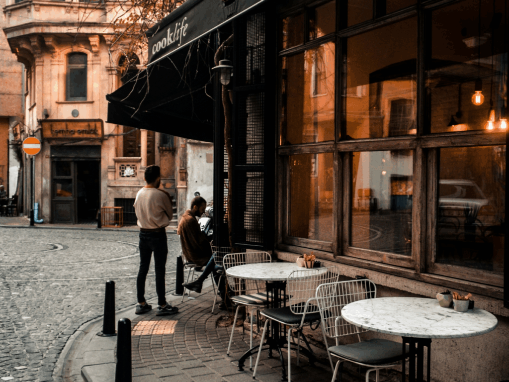 transformative travel; an image of open tables and a few patrons at a corner cafe to represent choosing places off the beaten path.