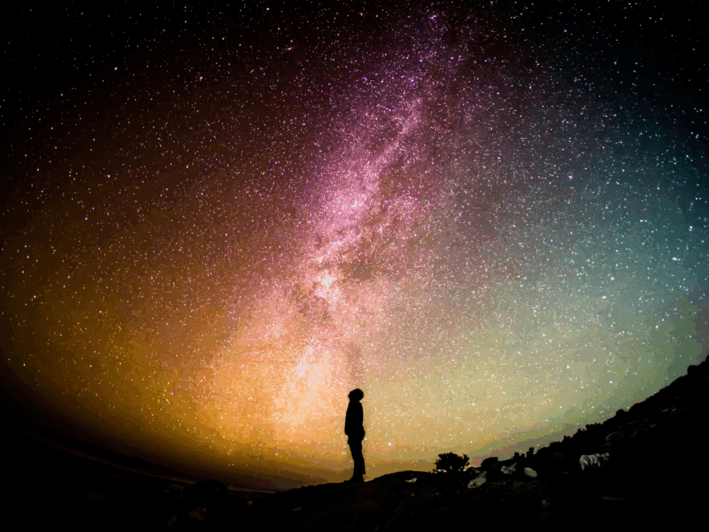 find inspiration; a human stares up at the night sky with colorful galaxies and swirling stars to symbolize finding inspiration