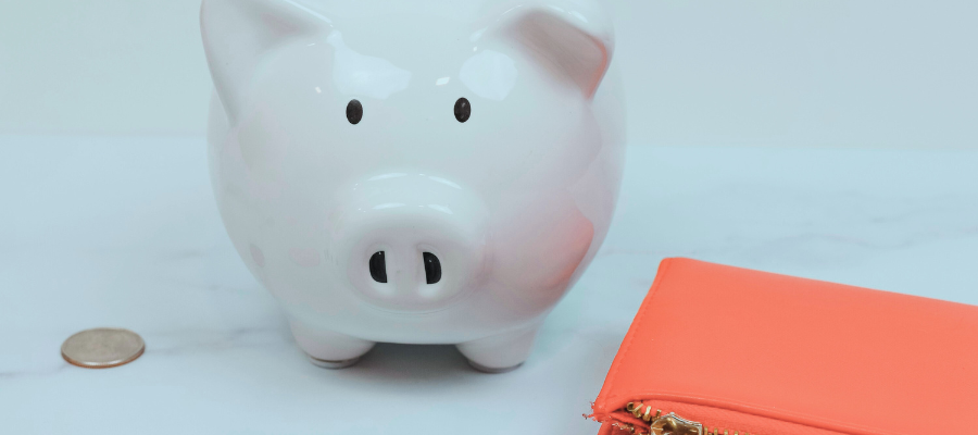 financial confidence; close up image of a piggy bank, coin, and red wallet represent the work it takes to achieve financial confidence