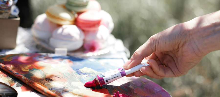 a quiet mind; image of a hand smearing paint on a palette with macarons in the background represents my mind-quieting experience in Paris