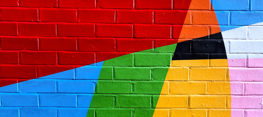 get out of your comfort zone; a colorfully painted brick wall represents getting out of your comfort zone and breaking down the brick walls keeping you small