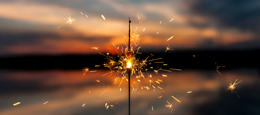 creative energy; Image of a hand holding a sparkler with the ocean in the background represents igniting your creative energy.