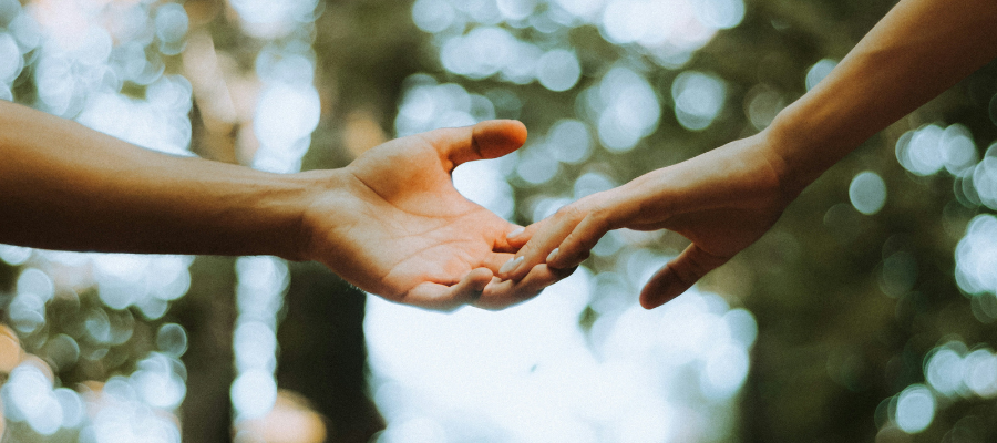a photo of two peoples' hands reaching for each other, touching at the fingertips, represents reaching for your audience to hold their hand and make them feel seen