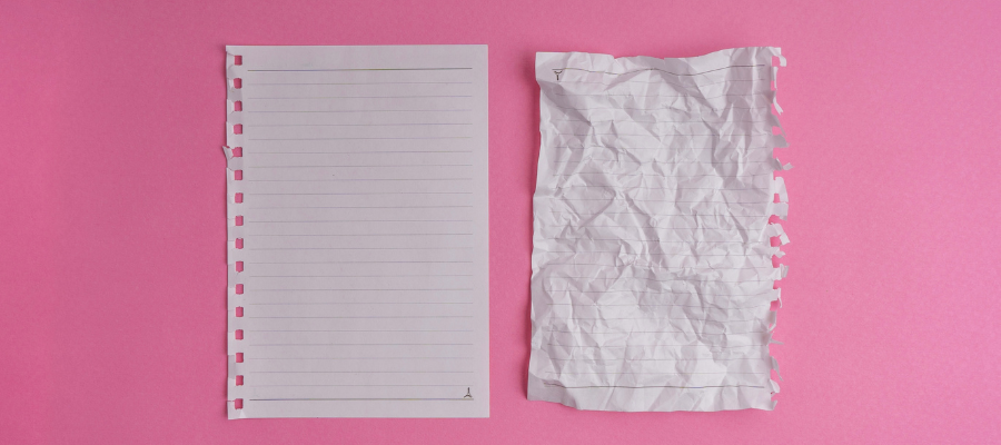 a fresh sheet of lined paper next to a smoothed out but crumpled piece of lined paper on a pink background represents holding two opposing ideas at once: the impossibility of your dream and its inevitability